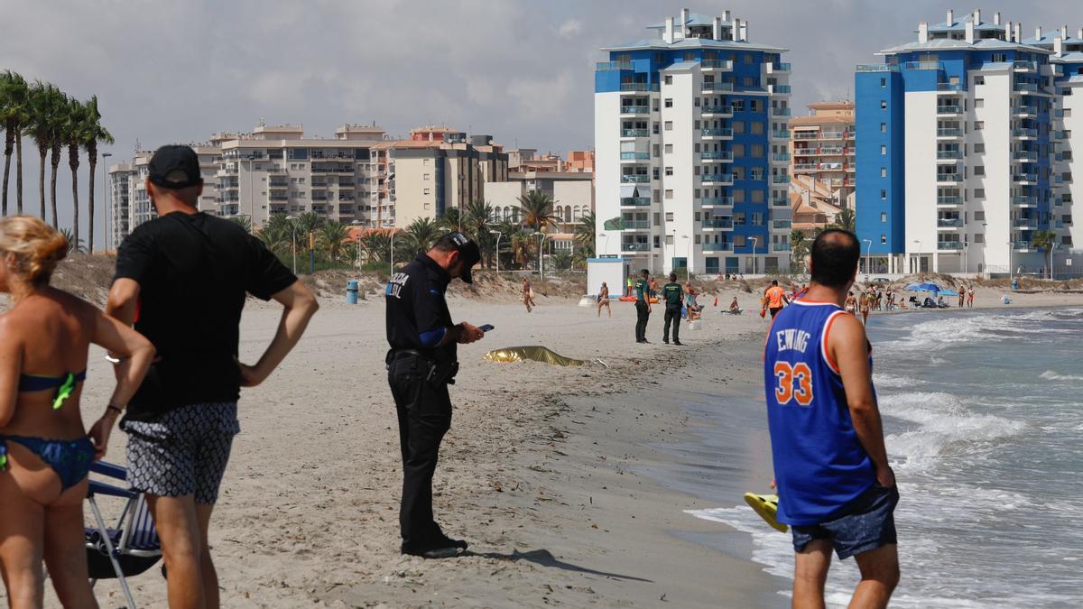 Bañistas de la zona observan el cadáver sobre la arena de La Manga, ayer. LOYOLA PÉREZ DE VILLEGAS