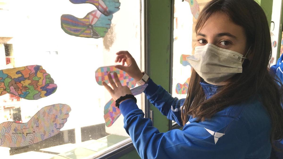 Una alumna del Colegio El Buen Pastor cuelga una huella mandala en la ventana de su clase.