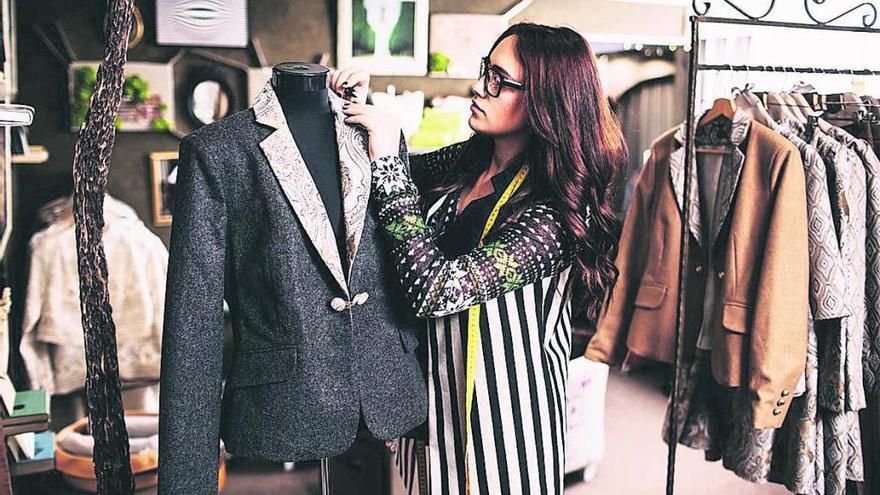 Una mujer mira una prenda de vestir en una tienda de ropa.