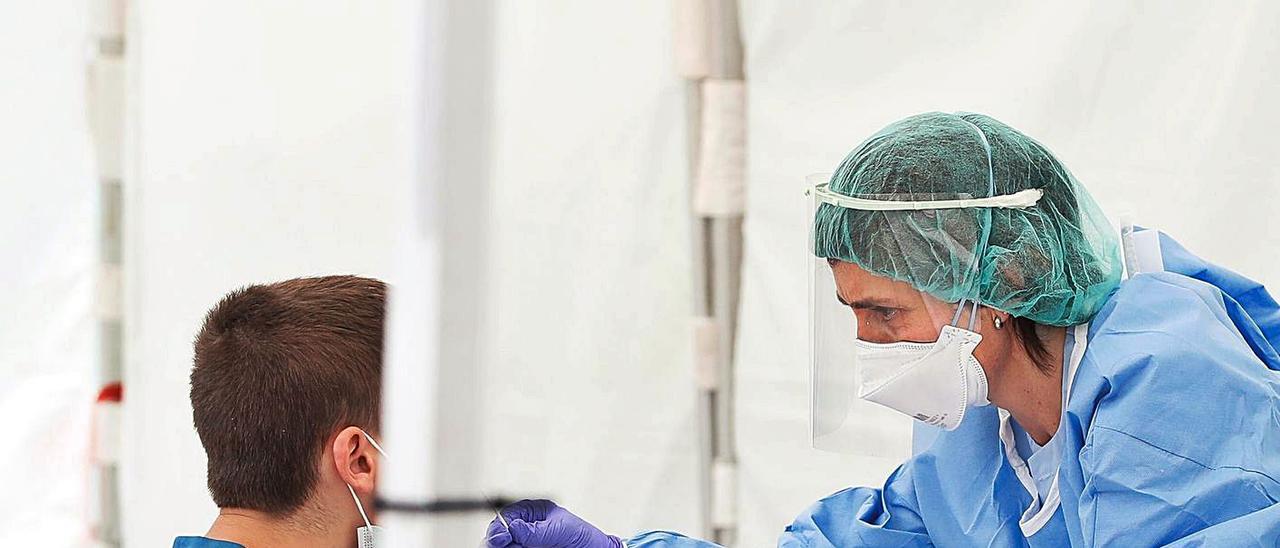 Una enfermera toma una muestra a un joven para hacer una PCR
