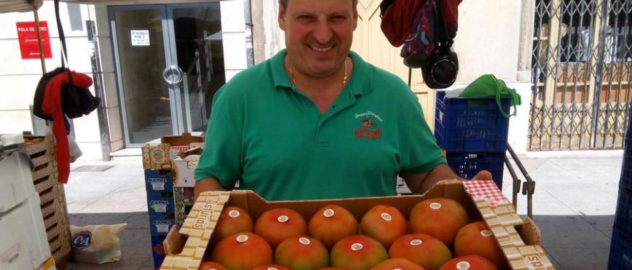 Richard Meana muestra una caja con tomates en su puesto de venta de la avenida Ildefonso Sánchez del Río de Pola de Siero.