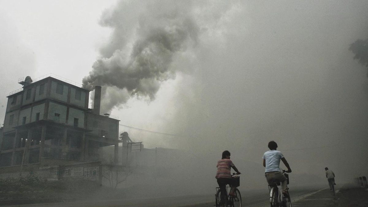 Unos ciudadanos pasan al lado de una central de carbón en China.