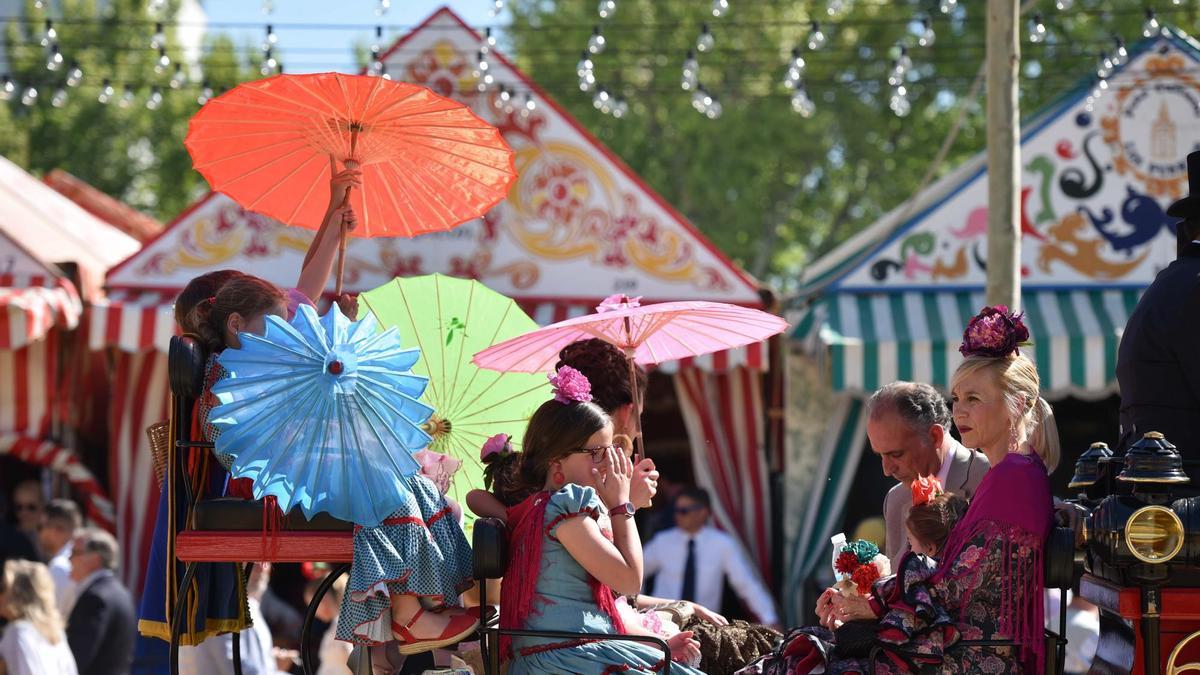 El paseo en familia en coche de caballos, una de las estampas más clásicas de la Feria de Abril de Sevilla. Aunque sea con sombrillas orientales. / Fotos: Jesús Barrera