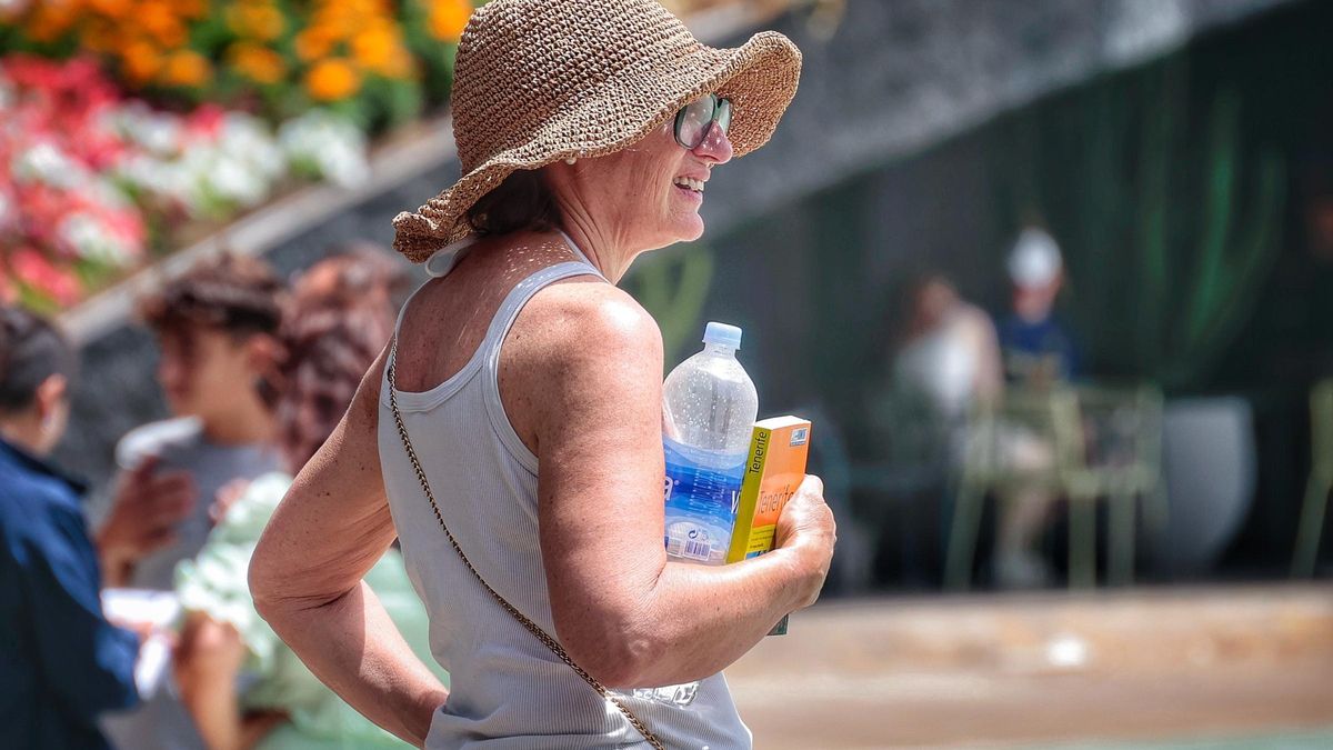 Una mujer se cubre con la cabeza con una pamela para evitar el calor.