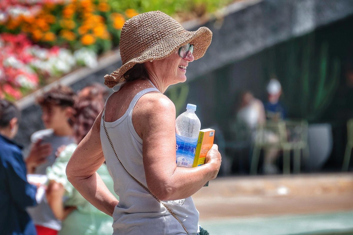 Una mujer se cubre con la cabeza con una pamela para evitar el calor.