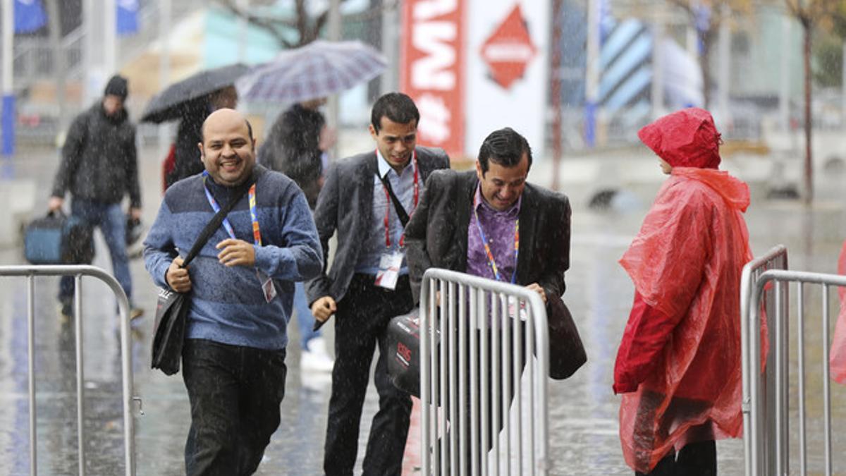 Visitantes del congreso de móviles bajo la lluvia.