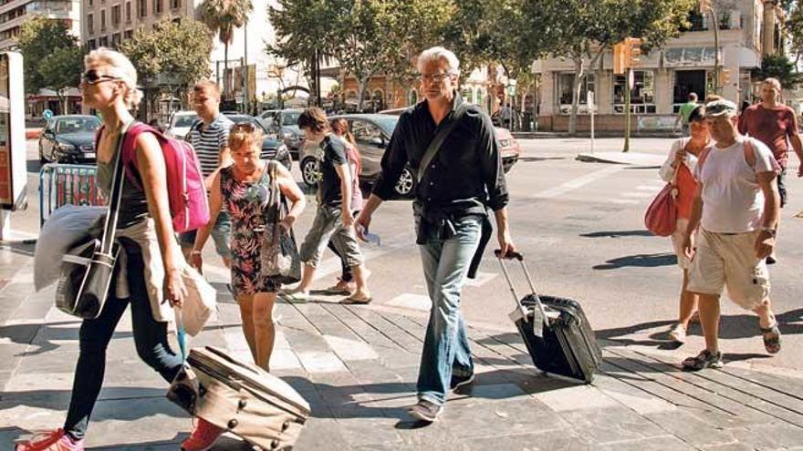 Dos turistas con sus maletas en la plaza España de Palma.