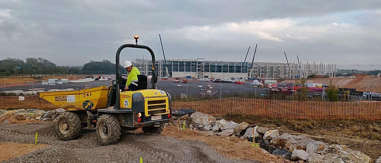 Obras en la parcela de Amazon en Bobes, con la nave al fondo, donde se aprecian las primeras planchas de hormigón colocadas a modo de fachada en la parte inferior del edificio. | P. T.