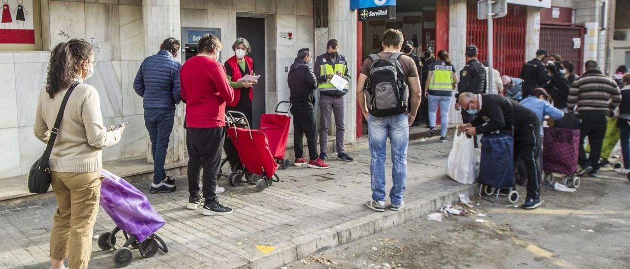 Un grupo de personas guarda cola en una despena solidaria en Alicante.  | ALEX DOMÍNGUEZ