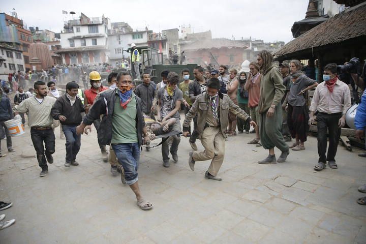 Un grupo de hombres lleva a una persona en camilla tras el terremoto en Katmandú