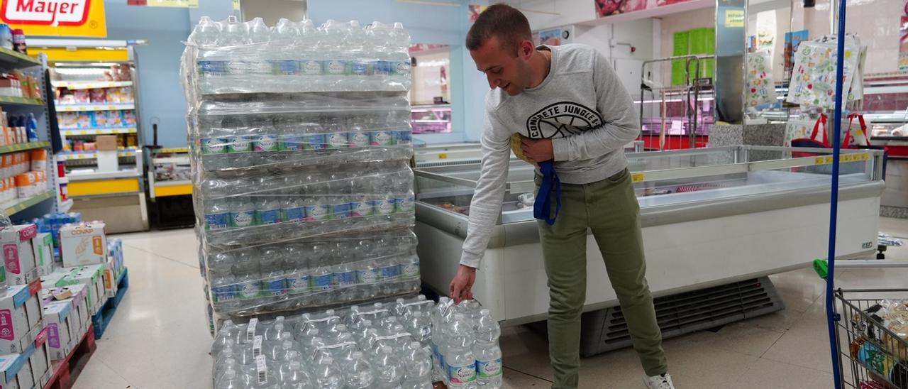 Un cliente con botellas de agua en un supermercado de Pozoblanco, hoy martes.