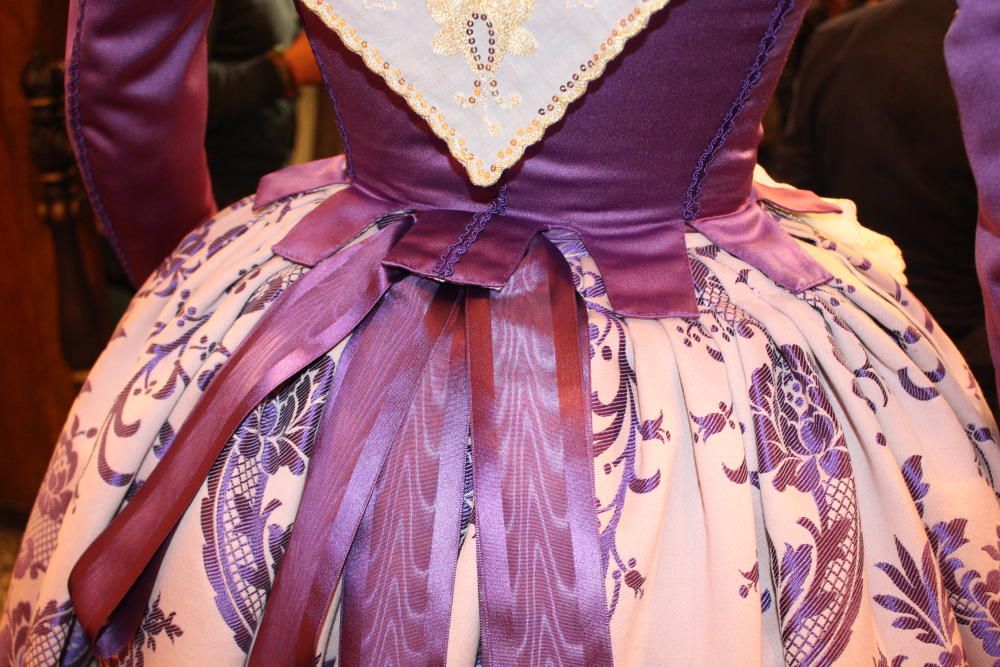 El traje consta de una falda en brocado con fondo rosa y dibujo morado a juego con el color del jubón. Guardapiés confeccionado al estilo del S. XVIII con el vuelo en cintura a pliegues. Jubón de finales del S. XVIII envarado, con influencia goyesca con adornos como pasamanería y borlas.