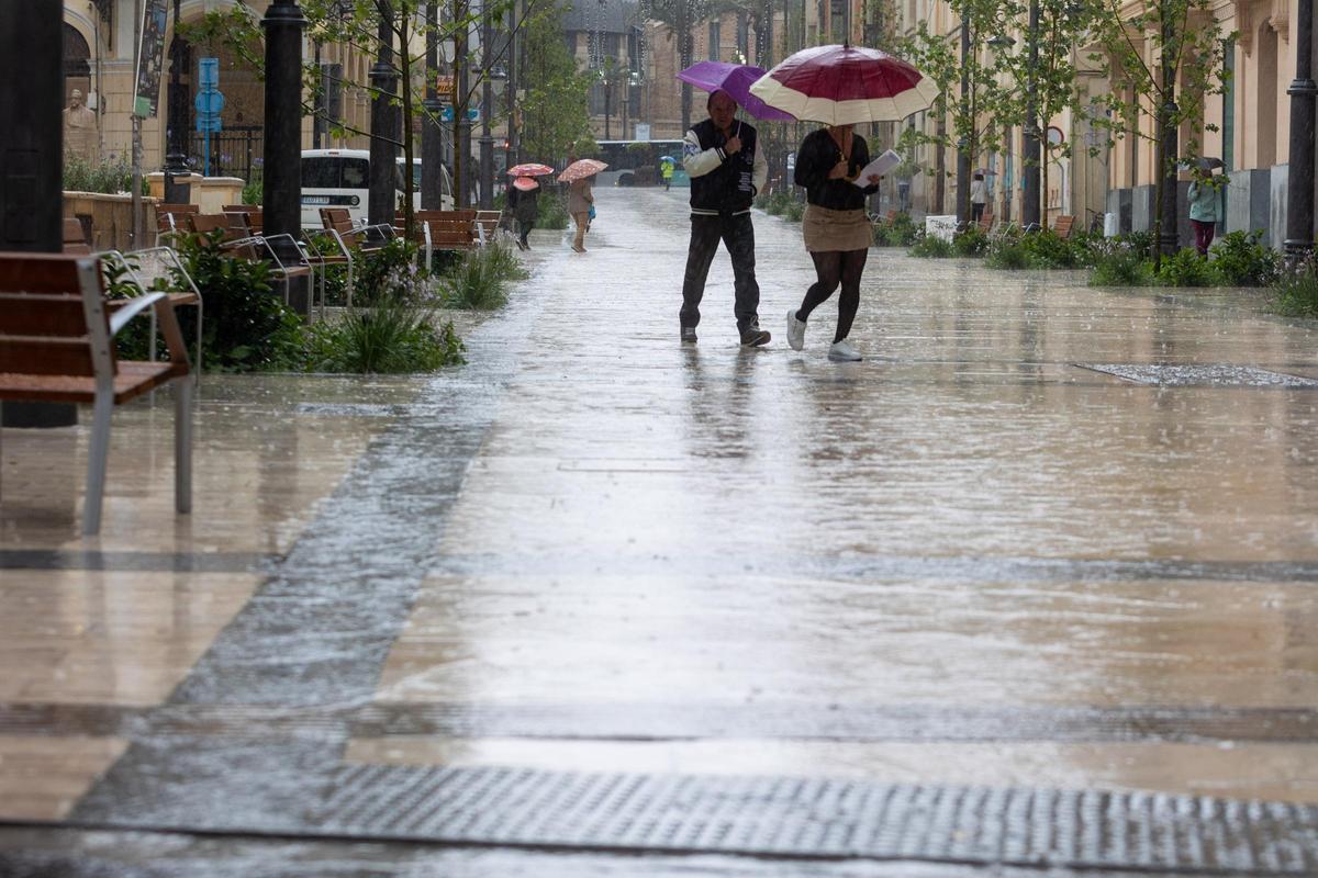 Personas bajo la lluvia en el centro de Alicante en mayo de este año.