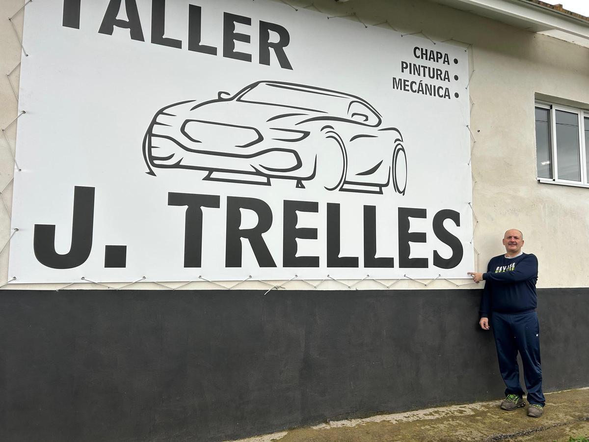 Javier Trelles frente al cartel ubicado en la fachada de su taller.
