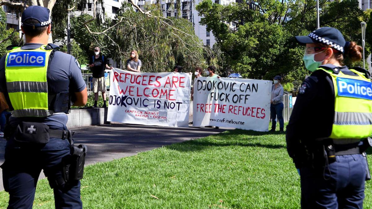 EDITORS NOTE: Graphic content / Pro-refugee activists carry banners outside a government detention centre where Serbia's tennis champion Novak Djokovic is reported to be staying in Melbourne on January 7, 2022, after Australia said it had cancelled the entry visa of Djokovic, opening the way to his detention and deportation in a dramatic reversal for the tennis world number one. (Photo by William WEST / AFP)