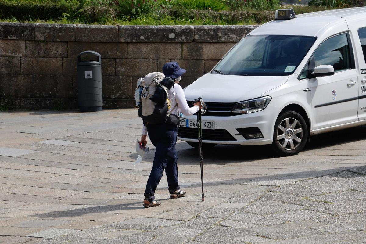 Un taxi junto a una peregrina en la zona vieja de Santiago de Compostela