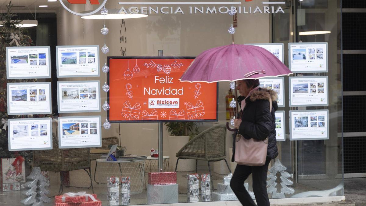 Una vecina de Carcaixent pasa ante el escaparate de una inmobiliaria en una imagen de este viernes.