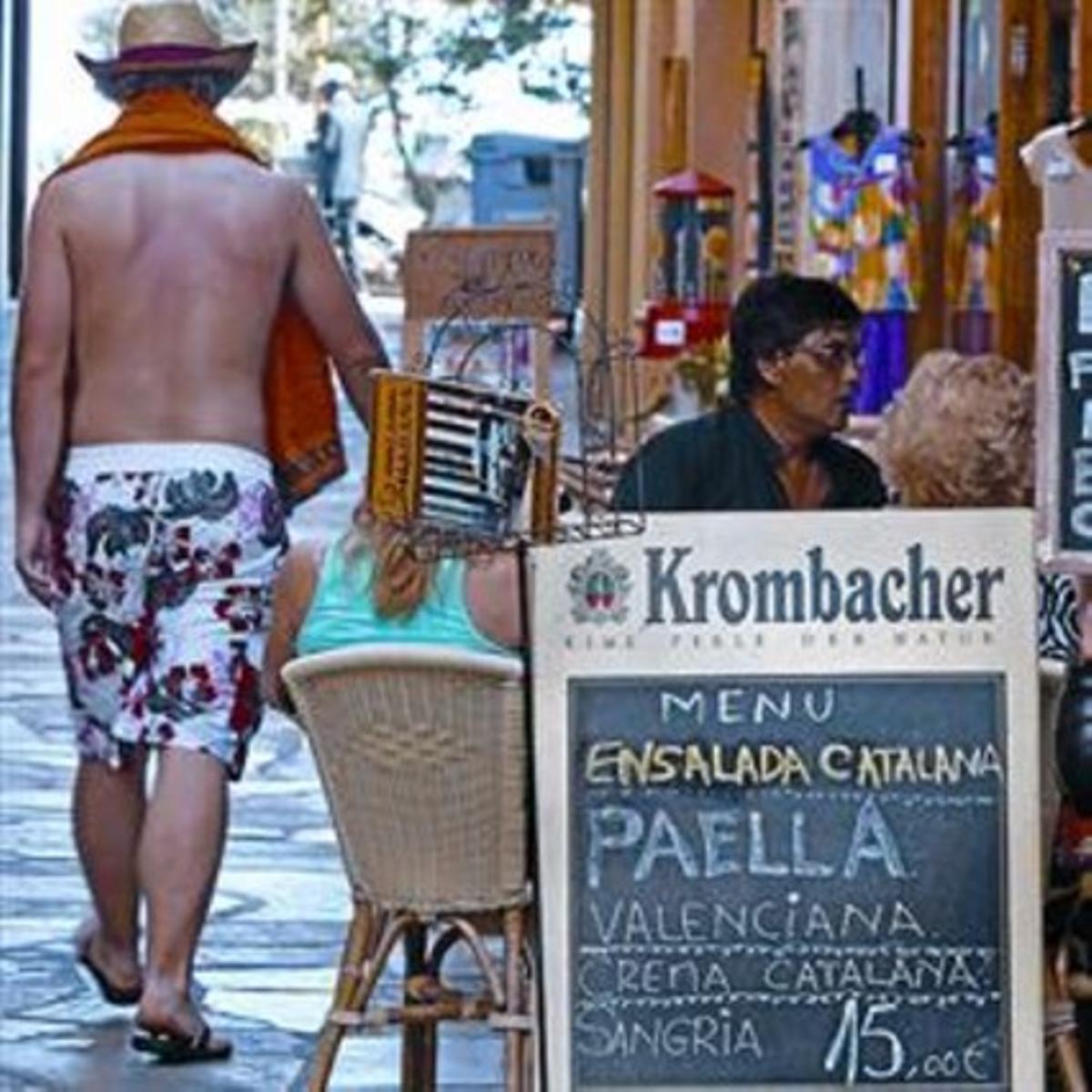 Dos turistas comen tras el cartel de un restaurante, en Lloret de Mar.