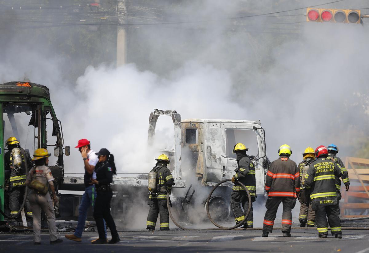 Integrantes del Cuerpo de Bomberos de Guadalajara intentan apagar un vehículo incendiado este domingo, en Guadalajara (México). EFE/ Francisco Guasco