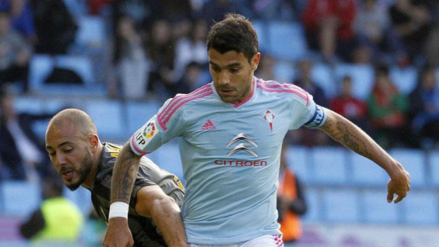 El centrocampista argentino del Celta de Vigo, Augusto Fernández (c), disputa el balón ante el delantero marroquí del Málaga, Nordin Amrabat (i), en el partido de la jornada 34  de la Liga BBVA celebrado en el estadio de Balaidos.