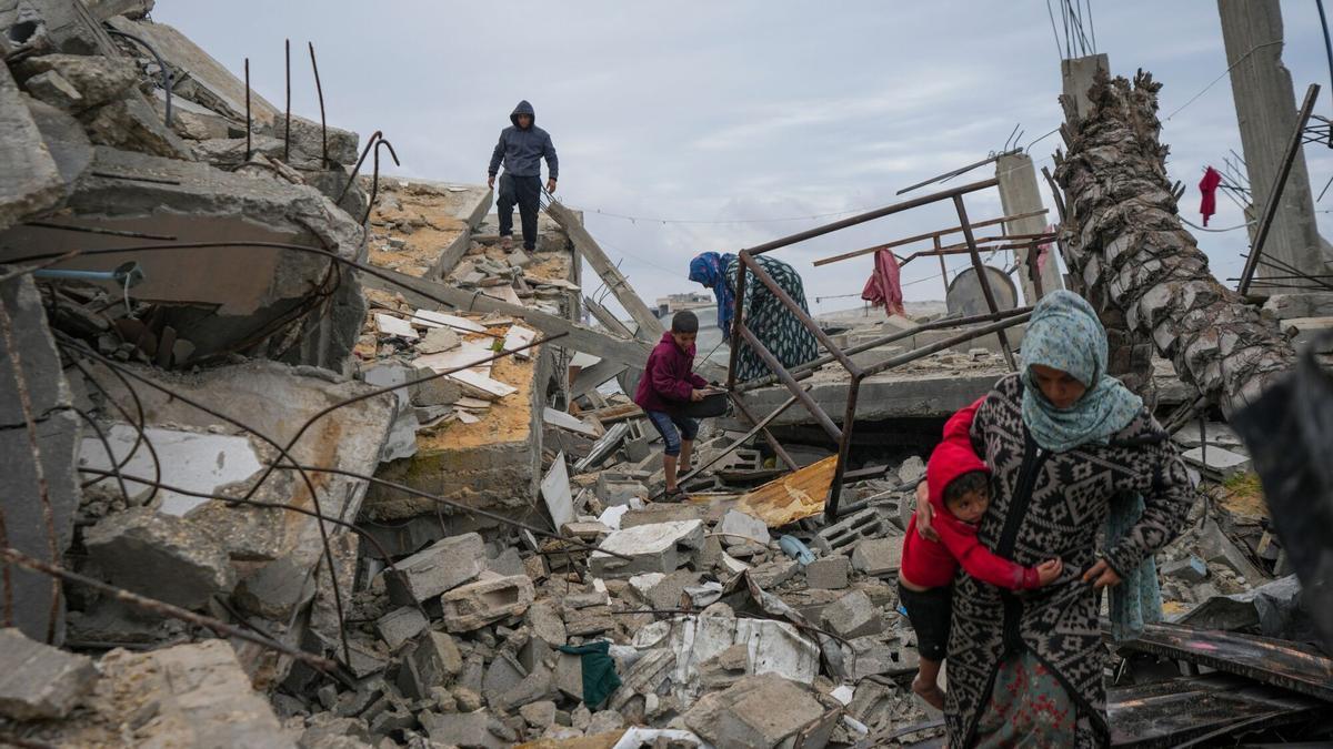 Fatima Rehan lleva en brazos a su hijo Mohammed, de dos años, mientras ella y otros miembros de la familia Rehan buscan entre los escombros de su casa, destruida por la ofensiva aérea y terrestre del ejército israelí contra Hamás en la Franja de Gaza.