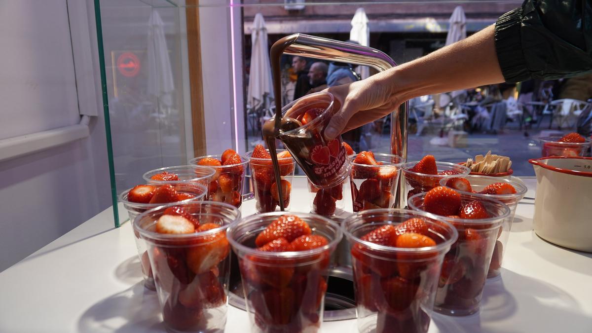 Vasos de fresas bajo la fuente de chocolate.
