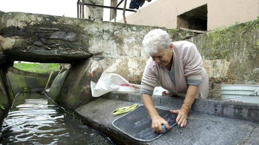 Una señora lavando la ropa en una acequia de Firgas, poco después de acabarse su restauración. | santi blanco