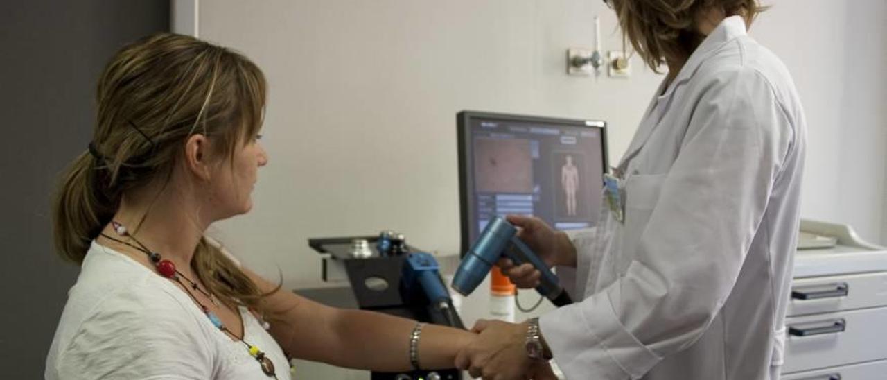 Una dermatóloga revisa un lunar a una paciente en una consulta del hospital de Son Llàtzer.