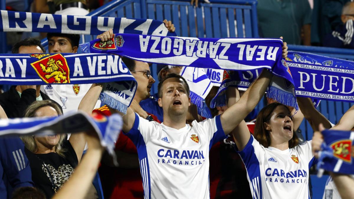 Varios aficionados animan al Real Zaragoza en La Romareda.