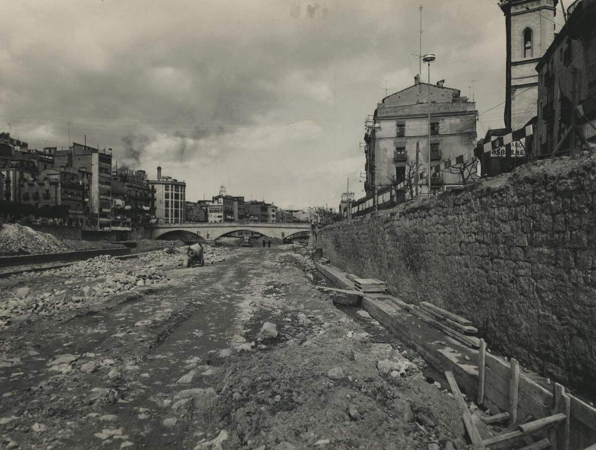 bres de construcció de la plataforma de la plaça Catalunya sobre el riu Onyar. Al fons, el pont de Pedra. En primer terme, restes de la porta d'en Vilà de l'antiga muralla del riu.