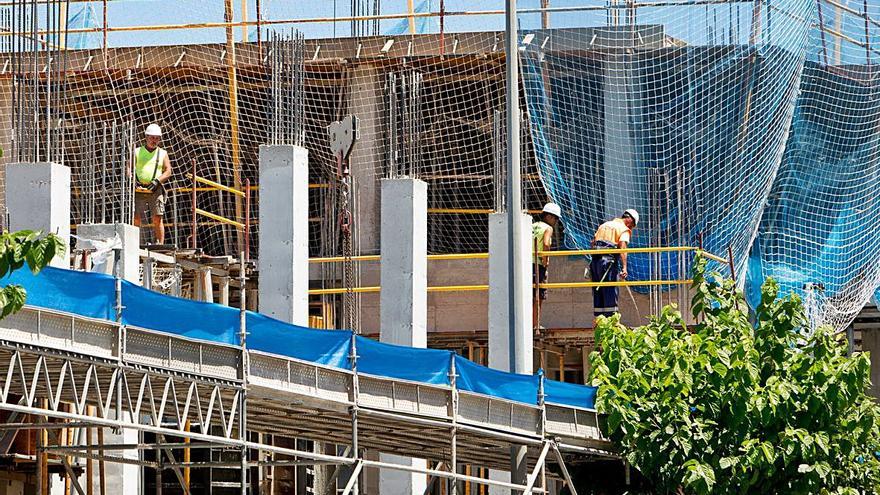 Operarios trabajando ayer en una obra de construcción en Alicante. Al lado, el Mercado Central de Elda abierto el festivo autonómico recuperable de Sant Joan. | JOSE NAVARRO/ÁXEL ÁLVAREZ