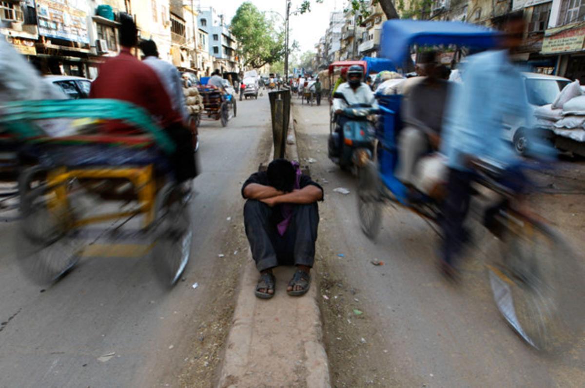Un treballador descansa a la mitjana de la carretera del mercat de Nova Delhi, a l’Índia.