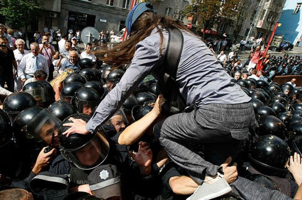 Una dona s’enfila al cap dels agents de policia durant una manifestació a Kíev contra una llei per augmentar l’estatus de l’idioma rus a Ucraïna.