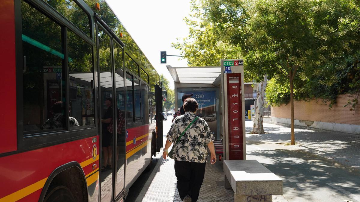Mujer esperando en una parada de autobús de TUSSAM en Sevilla durante un día soleado