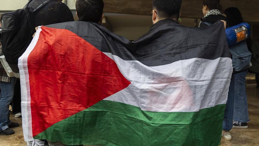 Estudiantes participantes en la acampada de la UV con una bandera palestina.