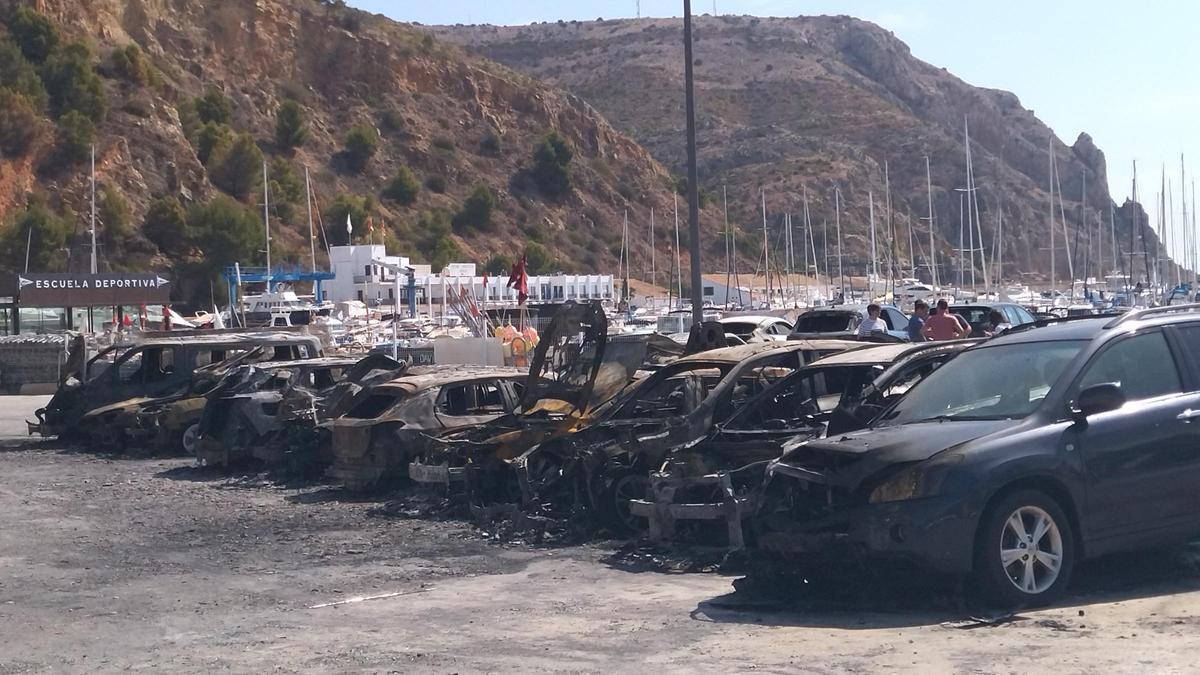 Los coches calcinados y, al fondo, el perfil del cabo de Sant Antoni