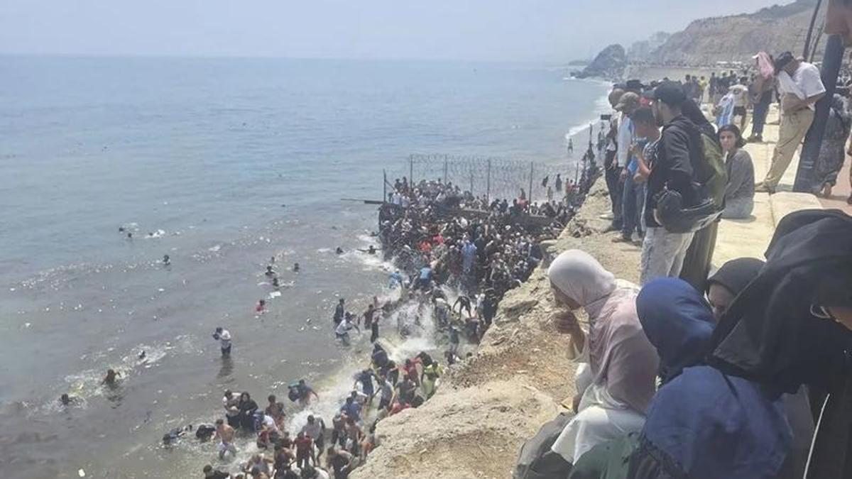 Migrantes entran en Ceuta a pie por el espigón.