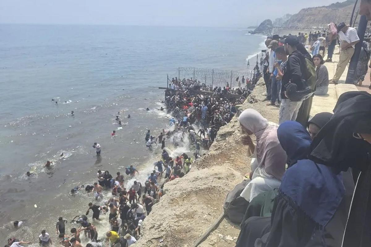 Migrantes entran en Ceuta a pie por el espigón.