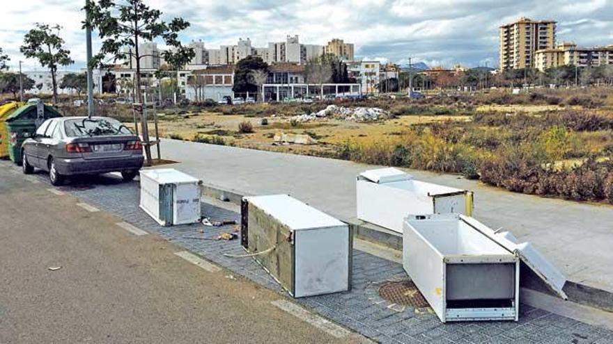 Cuatro neveras tiradas en la calle Felicià Fuster. Al lado, el solar con el vertedero.