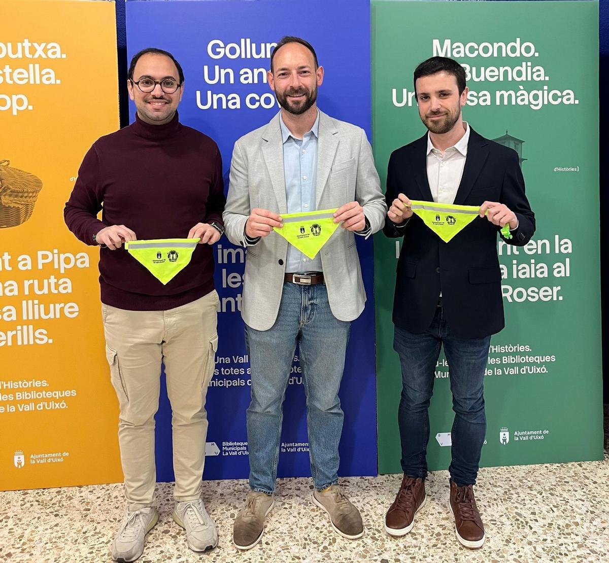 Los ediles Ximo Zorrilla y Jorge García, y el vicesecretario de la Junta Local Fallera, Fran Daniel, muestran los pañuelos fluorescentes para las mascotas.