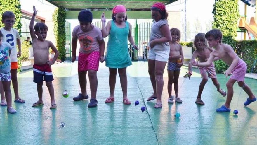 Varios niños y niñas bailando la peonza a la vez, ayer por la tarde en las piscinas de Los Salados.