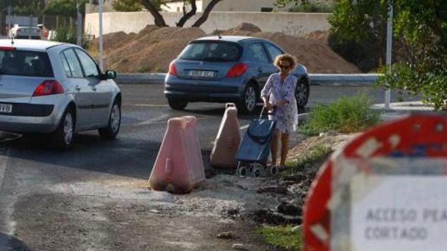 Una mujer caminando por un tramo donde hay una señal que anuncia el paso cortado.