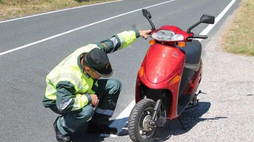 Un agente revisa el ciclomotor conducido por el detenido.  // FdV