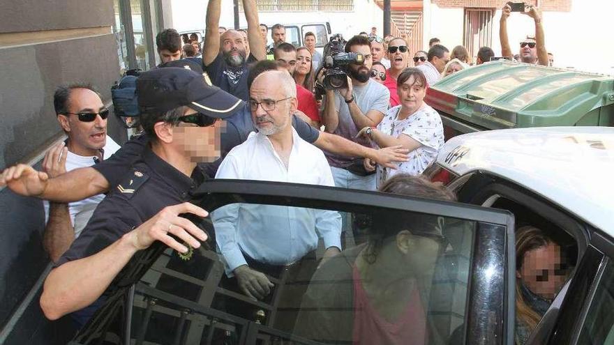 Un agente introduce en el coche policial a las dos mujeres relacionadas con la presunta estafa.