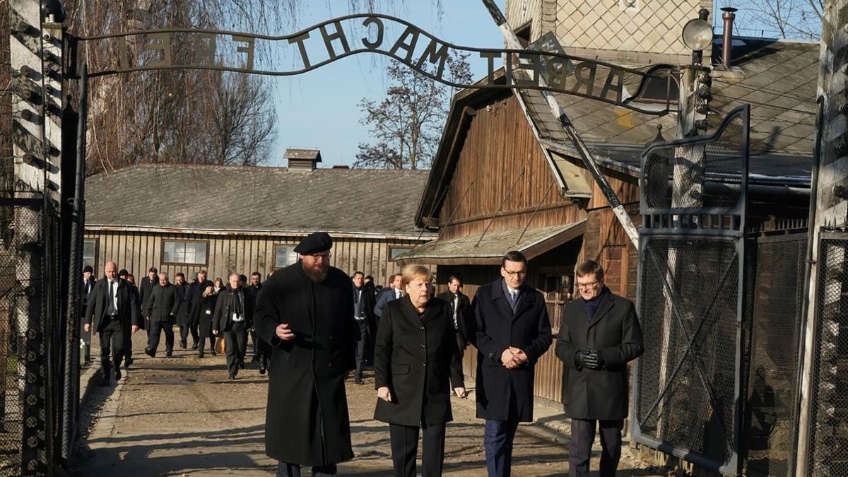 Angela Merkel cruza la puerta de entrada del campo de concentración de Auschwitz, bajo el cartel 'El trabajo os hará libres'.