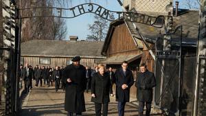 Angela Merkel cruza la puerta de entrada del campo de concentración de Auschwitz, bajo el siniestro cartel ’El trabajo os hará libres’.