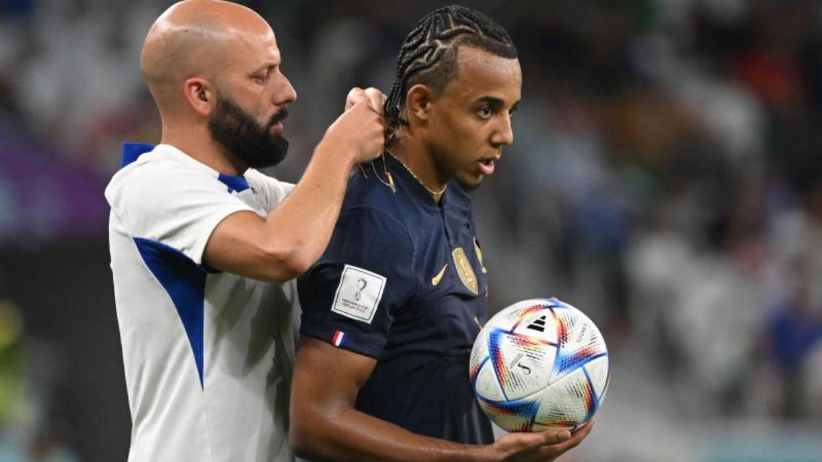 Jules Koundé, el defensor francés, con la ayuda de un asistente del cuerpo técnico de Francia quitándole el collar durante el partido ante Polonia.