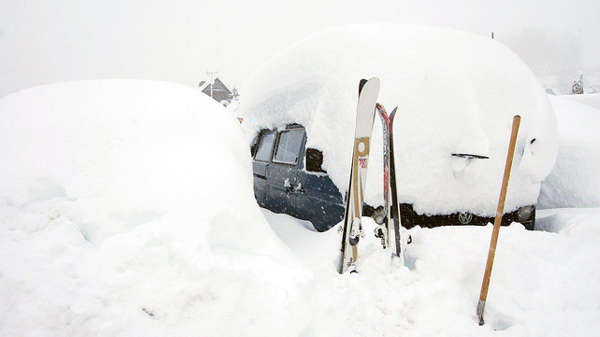 Un coche cubierto de nieve, junto a unos esquís, en el Vall d'Aran, este domingo
