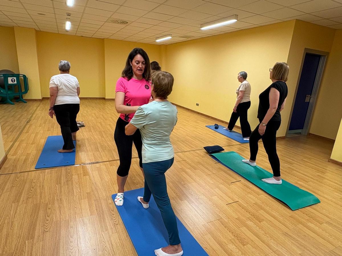Marta de la Fuente ayuda a las asistentes al curso a adoptar las posturas de yoga.