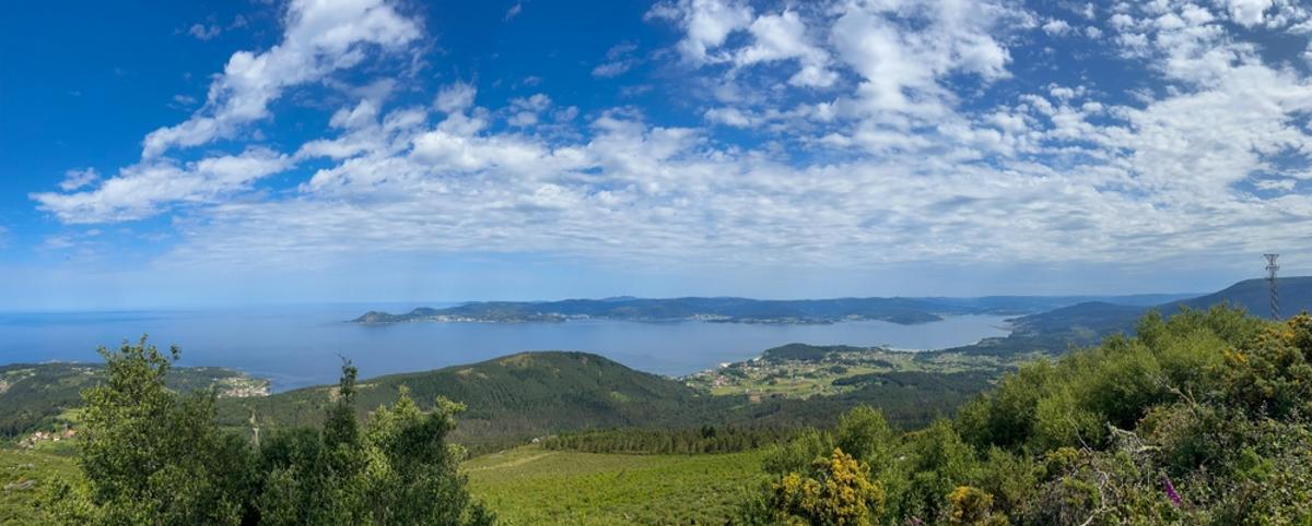 Una impresionante foto de Ria de Muros e Noia, Galicia, mostrando inmensas aguas, colinas verdes y pintorescas ciudades costeras.